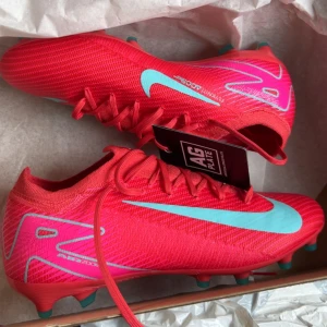 Nike fotbollsskor i rött och turkos - Snygga fotbollsskor från Nike i en stark röd färg med turkosa detaljer och snörning. Skorna har en låg profil och är tillverkade i syntetmaterial för bästa grepp och känsla på planen. Perfekta för dig som vill sticka ut på matchen. De är helt nya använda 1 gång, råkade köpa fel storlek. Det är PRO modellen. Kom privat för fler bilder eller mer information. Pris diskuteras så köp inte utan att diskutera!!!!!!