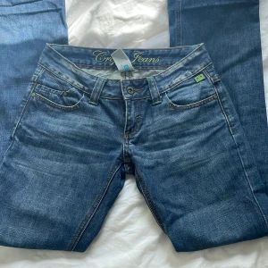 Lågmidjade jeans - Skitsnygga lågmidjade utsvängda jeans med coola gröna detaljer som inte kommer till användning längre💗 sparsamt använda och ena dragkedjan på vänstra bakfickan har gått sönder men det syns knappt☺️ skriv om ni har några frågor🥰 
