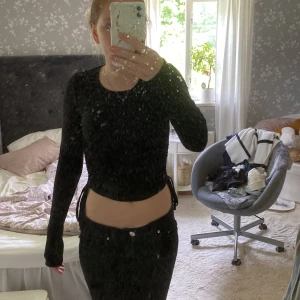 Svarta ribbad tröja med snörning XS - Svarta ribbad tröja från BubbleRoom i storlek XS. Kroppad coola tröja med snörningsdetaljer i sidorna. Mjukt stretchigt material som sitter tajt och följer kroppen. Perfekta för dig som gillar trendiga och bekväma plagg.