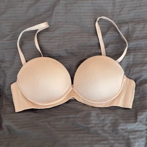 Beige super pushup bh  - Snygg beige bh med vadderade kupor och bygel för extra stöd. Justerbara axelband och hakknäppning bak. Mjuk och slät yta i syntetmaterial, perfekt under tighta plagg. Enkel och stilren design som smälter in under kläder. Storlek 75A och super push up!🩷