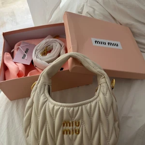 Miu Miu ”matelassé” väska  - Miu Miu Wander liten axelväska i matelassé.   Mått:  Djup	6 cm, Höjd	17 cm, Bredd	20 cm (kolla sista bilden så kan du se hur stor väskan är i jämförelse med min hand). Väskan är väldigt sparsamt använd med inga synliga skador på! Allt på bilden medföljer! Säljer billigare då detta var en gåva och har därav inget kvitto kvar. Möts upp i Stockholm området💕