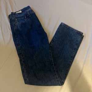 Levi's 501 blå jeans W30 L34 - Klassiska Levi's 501 jeans i mörkblå denim. Rak passform med fem fickor, knappgylf och snygga kontrastsömmar. Ikonisk läderpatch bak och röd Levi's-tagg vid bakfickan. Perfekta för en tidlös och avslappnad look.