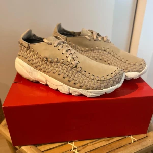  Nike footscape sneakers *DEADSTOCK* - Helt nya ! Aldrig andvända Unika beige Nike sneakers med flätad ovandel i mocka och textil. Skorna har vita, chunky sulor och snygg snörning. Perfekt för dig som vill sticka ut med en stilren men ändå annorlunda sneaker. Nike-logga bak på hälen och på plösen. DESDSTOCK 