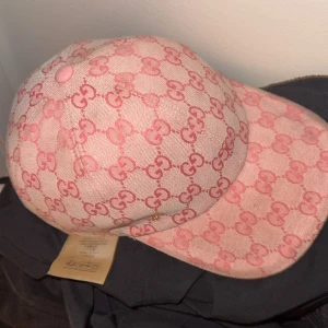 Gucci keps rosa  - Säljer en snygg rosa keps från Gucci med klassiskt GG-monogram i mörkare rosa över hela kepsen. Kepsen har böjd skärm och justerbar rem bak. Tillverkad i bomullsmix med exklusiv känsla och tydlig Gucci-label på insidan. Perfekt för dig som vill sticka ut med en lyxig accessoar.  Säljer då jag har tröttnat och använder andra kepsar. Byter gärna mot den blåa gucci kepsen.