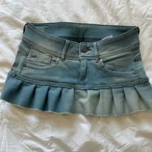 Jeanskjol med volang från G-Star RAW - Supersöt ljusblå jeanskjol från G-Star RAW med volangkant nedtill. Klassisk femficksmodell med knapp och dragkedja framtill. Midjemåttet är ca 35 cm rakt över. Hör av dig vid funderingar!🌟🩷
