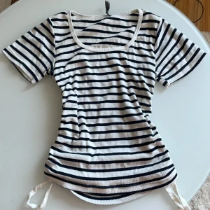 Randig ribbad topp från  - Superfin ribbad topp i vitt och marinblått med horisontella ränder. Modellen har snygga knytband i sidorna för en cool rynkad effekt. Köptes i Turkiet. Står S-M på bilden men passar Xs