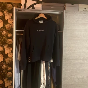 Marinblå Notre Succès hoodie med tryck - Marinblå hoodie från Notre Succès med vit text på bröstet och stort tryck på ryggen. Storlek S 