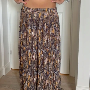 Långkjol med ormmönster från DRYS - Säljer en flowy långkjol från DRYS med snyggt ormmönster i bruna, gula och svarta toner. Kjolen har en avslappnad passform och är perfekt för dig som vill sticka ut med ett djurmönster. Hör av dig om du undrar något 🩷 jag på bilden är 168 och den är lite lång på mig men de beror också hur man sätter den i midjan!! Storleken står inte men jag skulle säga S/M