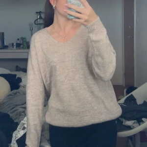 Beige stickad tröja från 157 - Supermjuk och basic beige stickad tröja från 157 med v-ringning och lång ärm. Perfekt för lager-på-lager och chill vibes. Passar dig som gillar en enkel och clean stil. Snygg till både jeans och kjol.