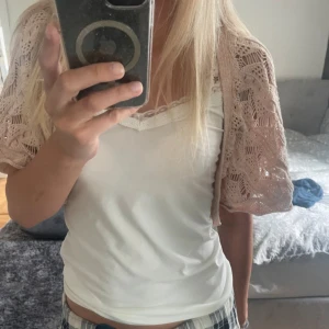 Bolero - Söt kort stickad bolero från KBL i 100% bomull. Boleron har ett öppet, virkat mönster med vågiga detaljer och korta ärmar. Perfekt att slänga över ett linne för en chill och somrig look.