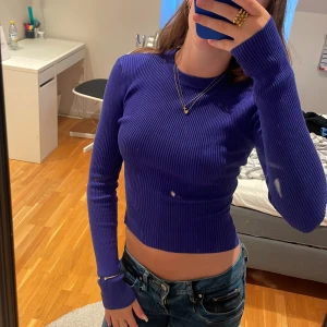 Ribbad blå långärmad tröja i xs - Säljer en tight, ribbad långärmad tröja i en snygg blå färg. Tröjan är croppad och har en rund halsringning.  Materialet är stretchigt och sitter riktigt snyggt på kroppen. Väldigt snygg att styla med mycket smycken. Köparen står för frakten 