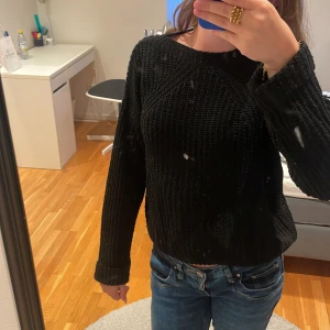 Svart stickad tröja med grov struktur i S - Svart stickad tröja med grov, ribbad struktur och rund hals. Tröjan har långa ärmar och en lite loose passform, perfekt att slänga på sig när det är kyligt. Jättesnygg och perfekt om man fryser. Köparen står för frakten 