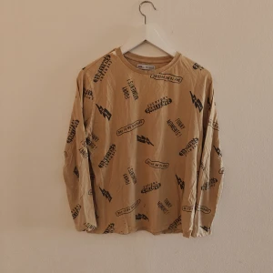 Zara tröja - Cool beige långärmad tröja från Zara Kids med svarta tryck och texter som 'EVERYDAY CHALLENGE' och 'DAY TO BE OUTSIDE'. Tröjan har avslappnad passform och är gjord i mjuk bomull, perfekt för chill dagar eller skolan.