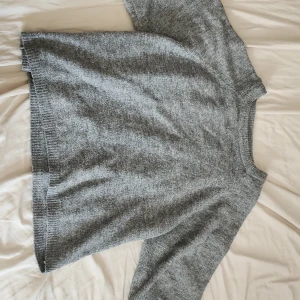 Grå stickad tröja från 157 - Mysig grå stickad tröja från 157 med avslappnad passform och trekvartsärmar. Tröjan har ribbade muddar vid hals, ärmslut och nederkant. Perfekt för lager-på-lager och chill dagar. Passar s/m 