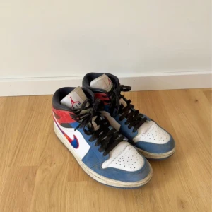  Jordan 1 Mid  - Nike Air Jordan 1 Mid med färgblock i blått, rött, vitt och svart. Skorna har broderad Swoosh i rött, blått, lila och orange, svart snörning och klassisk Jordan-logga på sidan. Använda men i fint skick!