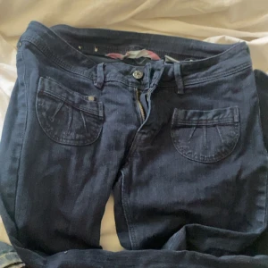 Mörkblå jeansbyxor med stora fickor - Snygga mörkblå jeansbyxor. Byxorna har dragkedja och knapp i midjan, passformen är normal.