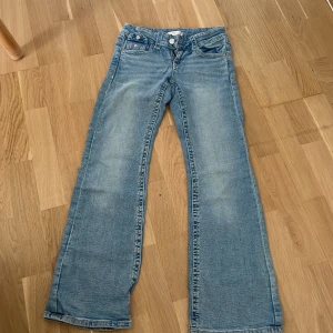 Blå bootcut jeans Gina Tricot 152 tall - Snygga ljusblå jeans från Gina Tricot i storlek 152. Modellen har bootcut-ben, klassiska fem fickor och coola detaljer på bakfickorna. Jeansen är i mjukt bomullsmaterial och har normal passform. Perfekta för en avslappnad och trendig look.