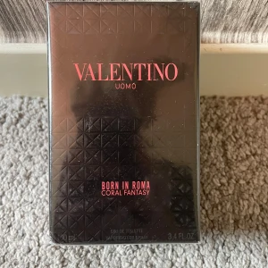 Valentino Uomo Born In Roma Coral Fantasy - Valentino Uomo Born In Roma Coral Fantasy är en herrparfym i en snygg svart kartong med geometriskt mönster och korallröd text. Flaskan innehåller 100 ml eau de toilette och har en lyxig och modern känsla. Perfekt för dig som gillar exklusiva dofter med stilren design.