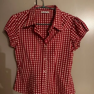 Rödvit rutig blus från VILA - Kortärmad skjorta/blus från VILA i rödvitt rutigt mönster. Knappar framtill och figurnära passform.