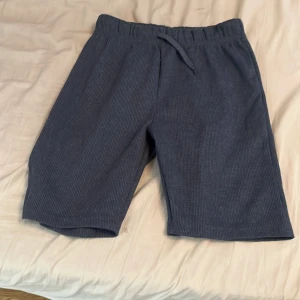 Blå ribbade shorts från Koton Kids - Mörkblå ribbade shorts från Koton Kids med elastisk midja och snörning. Sköna och avslappnade, perfekta för sommardagar. Tillverkade i mjukt bomullsmaterial och har en loose fit för extra komfort.