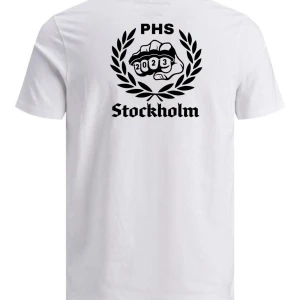 Vit PHS Stockholm t-shirt 2023 - Vit t-shirt från PHS med svart tryck fram och bak. På bröstet står det 'PHS' i gotisk stil och på ryggen finns ett stort tryck med knogjärn, lagerkrans och texten 'Stockholm 2023'. Klassisk passform och rund hals. Perfekt för student eller minne från året.