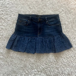 Jeanskjol med volang från Mos Mosh - En lågmidjad jeanskjol omsydd från ett par jeans. Midjemått tvärsöver - 37cm stretchig  Längd - 33cm