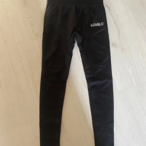 Svarta leggings från Lohilo XS - Svarta leggings från Lohilo i storlek XS. De har en bred, ribbad midja för extra komfort och en tight passform. Perfekta för träning eller chill, med Lohilo-logga framtill. Snygga och enkla att matcha med allt.