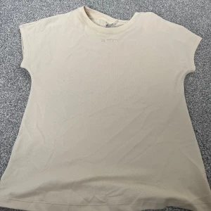 Beige träningströja  - Snygg beige träningströja från Aim'n. T-shirten har korta ärmar, rund halsringning och diskret broderad logga framtill. Perfekt för dig som gillar stilrena och sportiga vibes. Tröjan luftar väldigt mycket. Använd några få gånger bara. Köpt för 300kr. 