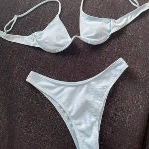 Ljusblå bikini med bygel - Snygg ljusblå bikini med bygel och tunna axelband. Överdelen har lätt vaddering och underdelen är högt skuren för en trendig look. Materialet är syntet med diskret struktur. Perfekt för stranden eller poolen i sommar!