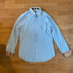 Burberry skjorta - Ljusblå burberry skjorta i storlek M. Väldigt bra skick utan skador eller fläckar. Perfekt nu till sommaren. Tveka inte att kontakta vid minsta lilla fundering.