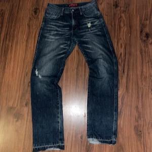 Levi's Nouveau Straight jeans blå - Säljer ett par Levi's Nouveau Straight jeans i mörkblå denim med slitningar och flared kanter nertill (slitningarna och kanterna är självgjorda) Klassisk femficksmodell med raka ben och snyggt tvättad look. Perfekta för dig som gillar en avslappnad och tidlös stil. Jeansen är i använt skick men jag tycker att det är just alla tecken på användningen som gör att jeansen blir unika och snyggare