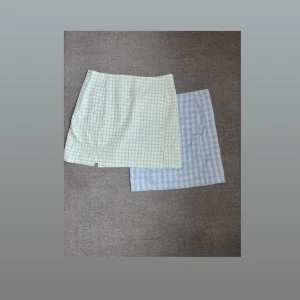 Två rutiga kortkjolar i pastell - Säljer två superfina kortkjolar i rutigt mönster, en i ljusblått och en i ljusgrönt. Båda har en liten slits framtill och är perfekta för dig som gillar en söt och trendig stil. Kjolarna är raka i modellen och har en fräsch vårkänsla.