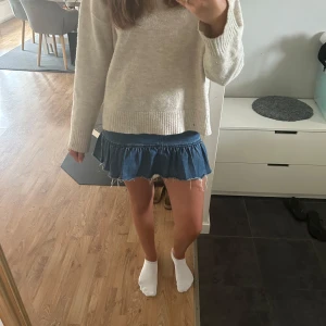 Jeanskjol med volang från Divided - Supersöt blå jeanskjol från Divided i kort modell med volangkant och råa kanter. Kjolen har dragkedja bak. 