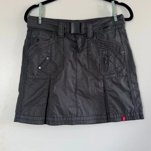 Minikjol i y2k stil från esprit  - Populär kjol från esprit i väldigt y2k stil.  Veck bak och fram till och ett skärp med midjan. Roliga detaljer på fickorna och skön i materialet.  Är stl 34 men passar även 36 skulle jag säga. Knappt använd så i fint skick.