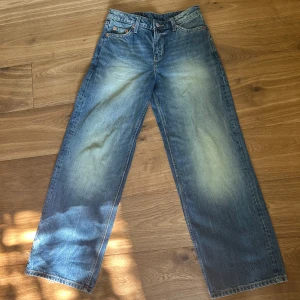 Wide jeans från Weekday i blå denim - Blå jeans från Weekday med breda ben och klassisk femficksdesign. Jeansen har en ljus tvätt med slitningar och råa kanter längst ner. Tillverkade i bomullsdenim och har en avslappnad, loose fit som ger en cool och avslappnad vibe.