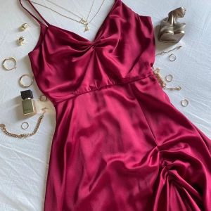 Cute cocktail dress from Amsterdam💕 - Supersnygg vinröd klänning köpt i Amsterdam med smala axelband och draperad v-ringning. Klänningen har en lätt rynkad detalj vid höften och följsam passform som ger en elegant siluett. Den är bara använd en gång så den är i mycket bra skick. Perfekt för dig som vill sticka ut med en lyxig vibe.