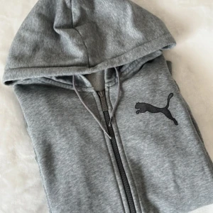 HOODIE  - Grå hoodie från Puma med dragkedja och luva. Storlek S från herravdelningen men är unisex! Nypris 399kr.