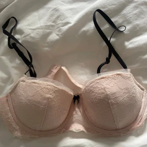 Ljusrosa spets bh  - Supersöt ljusrosa bh med vadderade kupor och spetsdetaljer. Svarta justerbara axelband och liten rosett framtill, säljer då den inte passar, storleken står inte i men skulle gissa storleken ksk är 70 A 75 A