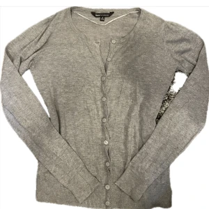 Grå kofta - En stilren grå kofta i storlek S med rund halsringning, långa ärmar och knäppning framtill med matchande knappar.