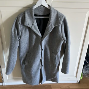 Grå trenchcoat  - Snygg grå trenchcoat i storlek L. Använd två gånger endast 