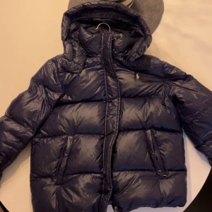 Ralph Lauren Jacket (S) - Snygg mörkblå dunjacka från Polo Ralph Lauren med huva och dragkedja. Jackan är quiltad och har två fickor framtill samt den klassiska loggan på bröstet. Perfekt för kalla dagar och riktigt skön att bära.