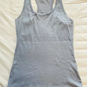 Ljusgrå linnetopp från Gina Tricot - En enkel och stilren ljusblå linnetopp från Gina Tricot. Modellen är klassisk med brottarrygg och rundad halsringning⭐️storlek L men känns mer som en M