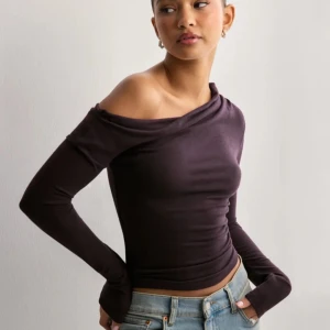 Burgundy Assymetrisk Topp - Trendig mörklila topp med offshoulder-design och långa ärmar. Snygg och figurnära passform som passar perfekt till jeans eller kjol. Materialet är mjukt och stretchigt för en bekväm känsla. Aldrig använt!