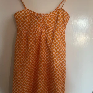 Orange blommig sommarklänning - Fin orange klänning från H&m skulle säga att den är ganska kort och är i nytt skick är i strl 32 och säljer för 30:-  är knälång