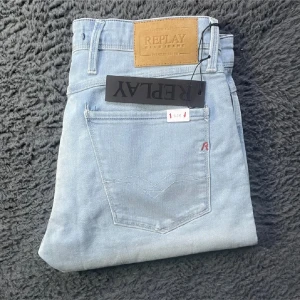 Ljusblå Replay jeansbyxor - Säljer ett par ljusblå jeansbyxor från Replay med klassisk femficksdesign och läderpatch bak i midjan. Byxorna har raka ben och diskret Replay-logga på bakfickan. Perfekta för dig som gillar stilrena och bekväma jeans.