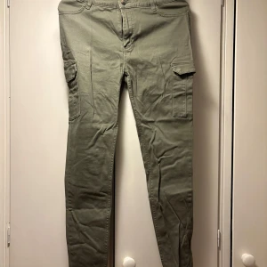 Olivgröna cargopants från 157 - Snygga olivgröna cargopants från 157 med klassiska sidofickor och smal passform. Byxorna har normal midja och är perfekta för en avslappnad stil. Tillverkade i mjuk bomull för extra komfort.