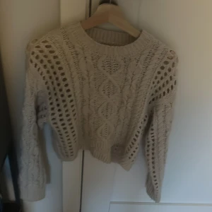Beige stickad tröja från Zara - Säljer en beige stickad tröja från Zara med snyggt hålmönster och flätstickade detaljer. Använd fåtal gånger!