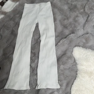 Vita ribbade byxor från Kappahl - Säljer ett par vita ribbade byxor från Kappahl. Byxorna har en rak passform med lätt utsvängda ben och är tillverkade i ett mjukt, stretchigt material. Perfekta för en avslappnad och trendig look.