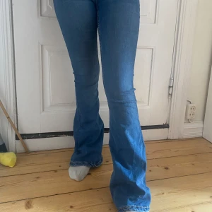 Blå bootcut jeans - Säljer ett par klassiska blå bootcut jeans med normal passform och hög midja. Jeansen har en snygg utsvängd benform och är tillverkade i ett mjukt denimtyg. Perfekta för dig som gillar en retroinspirerad look. Från lager 157, jag har dessa i byxor i Xs, S och M som går att köpa