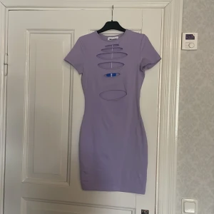 Ljuslila tight klänning med cut-outs från Sixth June - Säljer en ljuslila tight klänning från Sixth June med flera ovala cut-outs framtill. Klänningen har korta ärmar och är tillverkad i ett stretchigt material som sitter snyggt på kroppen. Perfekt för dig som vill sticka ut med en trendig look.